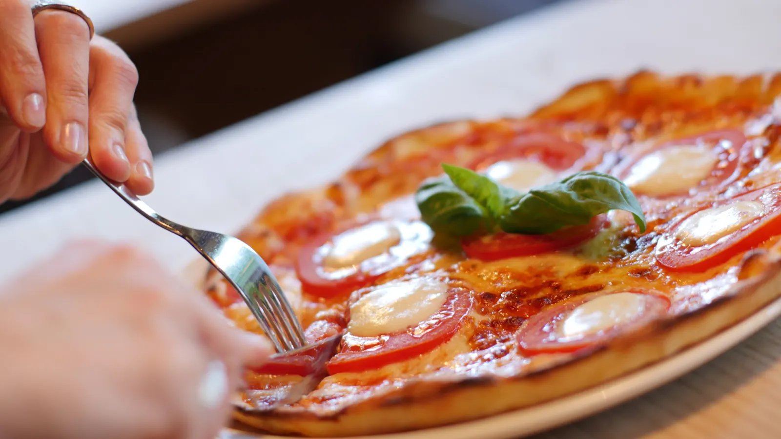 A margherita pizza with basil, a fork lifting a slice